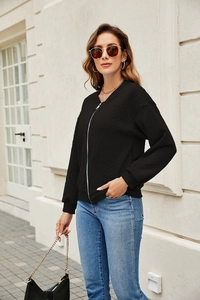 Detail of black zip-up jacket featuring textured ripple fabric and silver metal hardware
