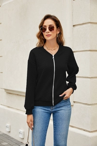 Detail of black zip-up jacket featuring diamond textured fabric and silver metal zipper
