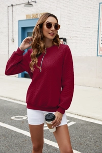 Detail of burgundy zip-up sweatshirt featuring a textured diamond knit pattern