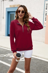 Detail of burgundy half-zip sweatshirt featuring a textured diamond knit pattern and metal zipper
