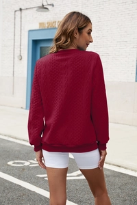 Detailed close-up of dark red knit sweater featuring cable and honeycomb texture