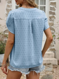Détail de la blouse bleue à manches courtes avec texture à pois et pli dans le dos