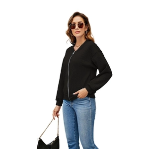 Detail of black zip-up jacket featuring diamond quilted texture and ribbed cuffs