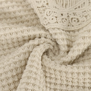 Detail of beige waffle knit fabric with delicate lace trim on the hem of a women's top