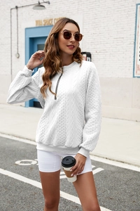 Detail of white cable knit sweatshirt featuring a black half-zip and thick textured fabric