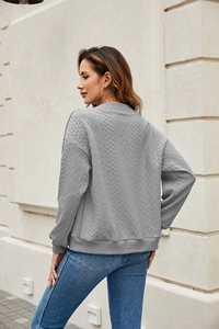 Detail view of grey cable knit long sleeve sweater texture and ribbed cuff design