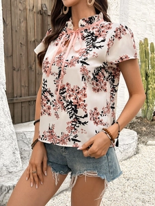 Detail of ruffled stand collar and pink satin bow on floral print short sleeve blouse
