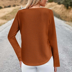 Detail of caramel waffle knit long sleeve top showing rich texture and curved hemline