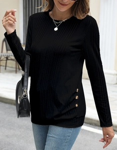 Detail view of black ribbed knit top with decorative brown buttons on the side hemline