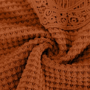 Macro detail of terracotta crochet lace trim and textured diamond knit fabric on t-shirt