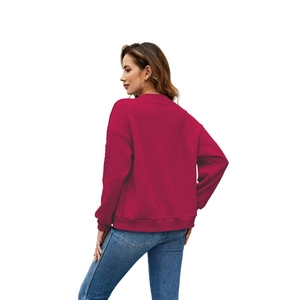 Detail of the rose red sweatshirt showing fine diamond knit texture and ribbed cuffs