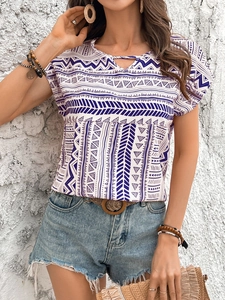Detail of bohemian white blouse showing blue geometric patterns and cutout lace-up neckline