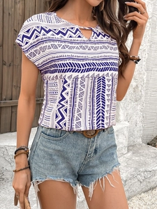 Detail of bohemian geometric print t-shirt with cutout neckline and frayed denim shorts