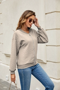 Detail of oat-beige zip-up sweater showing cable knit texture and ribbed stand collar