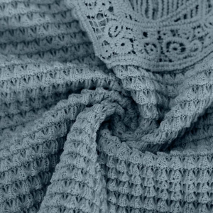 Detailed close-up of light blue waffle knit fabric with elegant lace trim texture