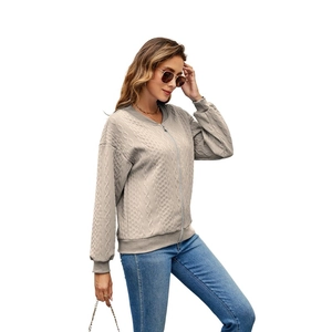 Detail of cable knit texture and zipper closure on a beige women's bomber jacket