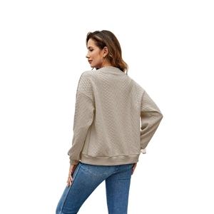 Detail of beige cable knit texture and drop shoulder design on a casual sweater