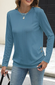 Detail of ribbed knit fabric texture and decorative buttons on a long sleeve blue top