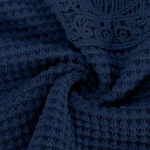 Close-up of navy blue crochet lace fabric showing intricate hollow floral patterns