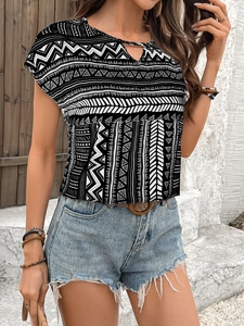 Detail of bohemian geometric print blouse with neck cutout and casual frayed denim shorts