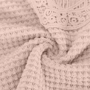 Close-up of pink waffle texture fabric with intricate floral lace trim on women top