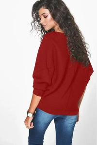 Détail d'un pull en maille rouge avec manches chauve-souris et poignets côtelés