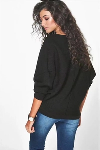 Détail d'un pull en maille noire avec manches chauve-souris et coupe décontractée