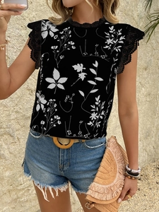 Detail einer schwarzen ärmellosen Bluse mit weißem Blumendruck und Spitzenbesatz am Saum