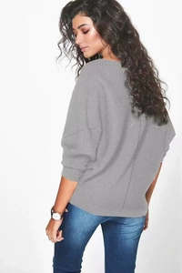 Détail du pull en maille grise à manches chauve-souris avec texture côtelée et ample
