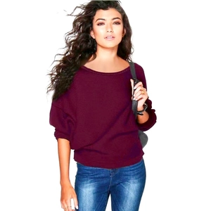 Détail d'un pull en maille bordeaux à manches chauve-souris et d'un jean bleu délavé