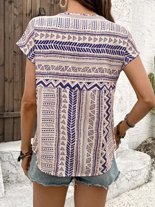 Detail view of women's short sleeve top featuring geometric print and back pleat detail