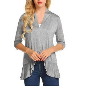 Detail of light gray knit cardigan featuring three-quarter sleeves and ruffled hem design