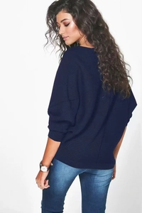 Détail du pull en tricot bleu foncé montrant la texture côtelée et les manches chauve-souris