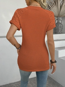 Detailed macro view of orange waffle knit texture and hollow-out lace design on the sleeve