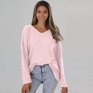 Detail of light pink waffle knit fabric on a loose V-neck long sleeve sweater for women
