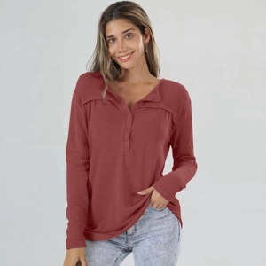 Detail view of brick red waffle knit texture and buttoned henley neckline on long sleeve top