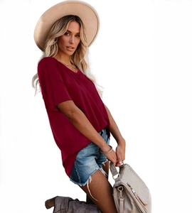 Vue latérale d'une femme en t-shirt bordeaux à col en V avec un short en jean
