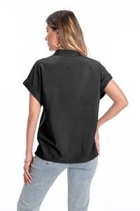 Detail view of black cotton linen shirt featuring textured fabric and rolled cuff design