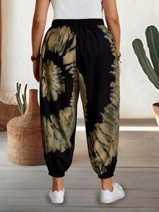 Detail view of high waist harem pants with tan tie-dye floral patterns and elastic cuffs