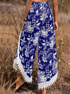 Détail d'un pantalon bohème large avec motifs floraux et bordures en dentelle blanche