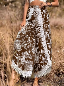 Détail d'un pantalon bohème à jambes larges avec dentelle blanche et franges sur tissu marron