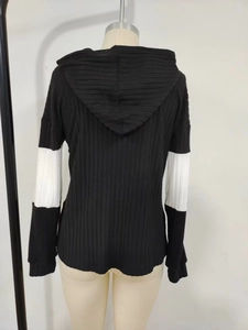 Détail d'un haut à capuche et manches longues avec coutures contrastées noir et blanc et maille