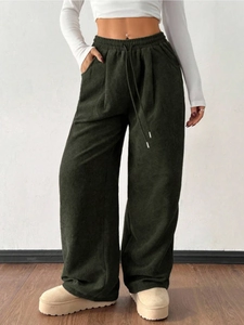 Detail of dark green corduroy trousers with elastic drawstring waist and side pockets