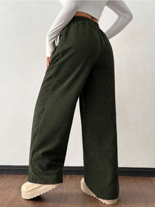 Detail view of deep green corduroy wide-leg pants showing texture and high-waist drape