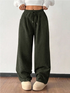 Detailed texture of dark green corduroy high waist trousers with drawstring waist
