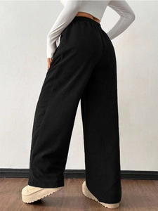 Detail of black corduroy wide-leg pants showing textured vertical ribs and loose fit design