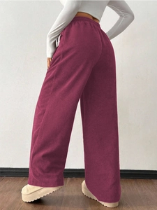 Close-up of wine red corduroy wide-leg pants showing elastic high waist and fabric texture