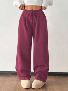Detail view of burgundy corduroy trousers with elastic waistband and adjustable drawstring