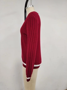 Close-up of deep red ribbed knit cardigan with white stripe details on cuffs