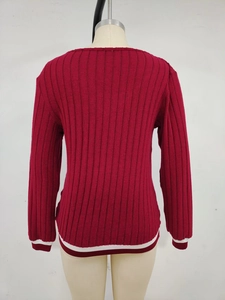 Detail of red knit sweater featuring ribbed texture and striped rib-knit cuffs and hem